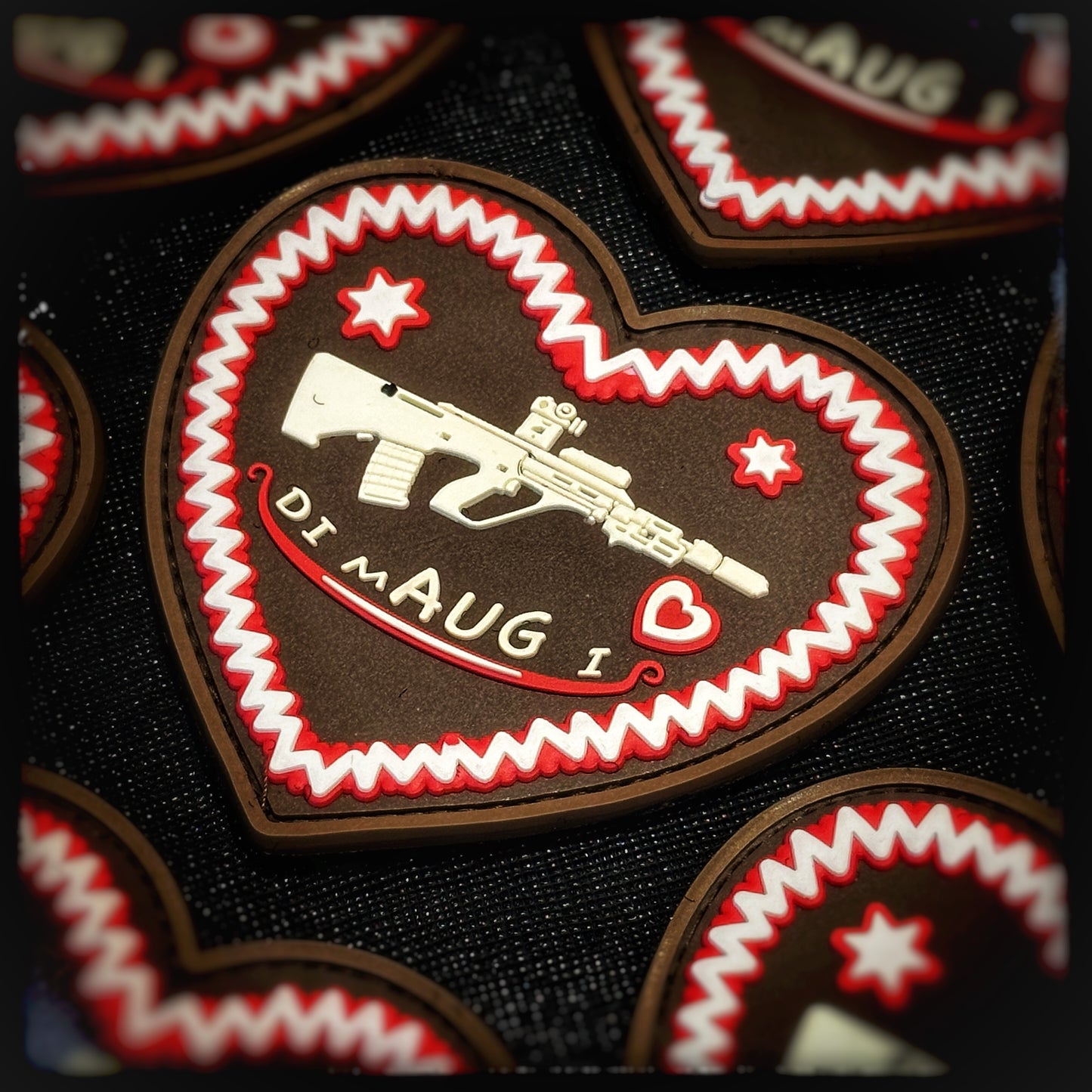 3D PVC Patch with velcro: Lebkuchenherz "Di mAUG I" The romance of the folk festival now also accompanies you into the field! 🎯💥 Whether you're a die-hard fan or proud bearer of the service rifle, this patch combines tradition with tactical humor. Designed in the classic gingerbread heart shape, it shows an STG77 aka. Army Universal Rifle (AUG) and the tongue-in-cheek lettering “I mAUG Di” - a playful allusion to “I like you”. Patchworld. patchworld.net